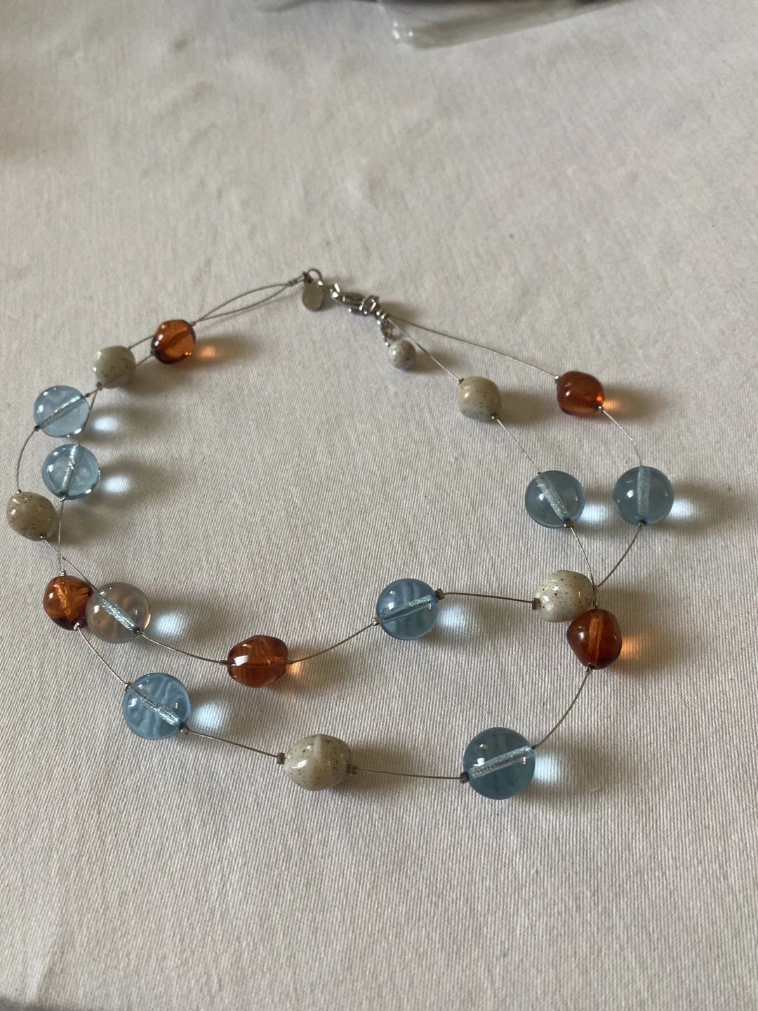 Triple-strand necklace with blue, brown, and speckled beige plastic beads
