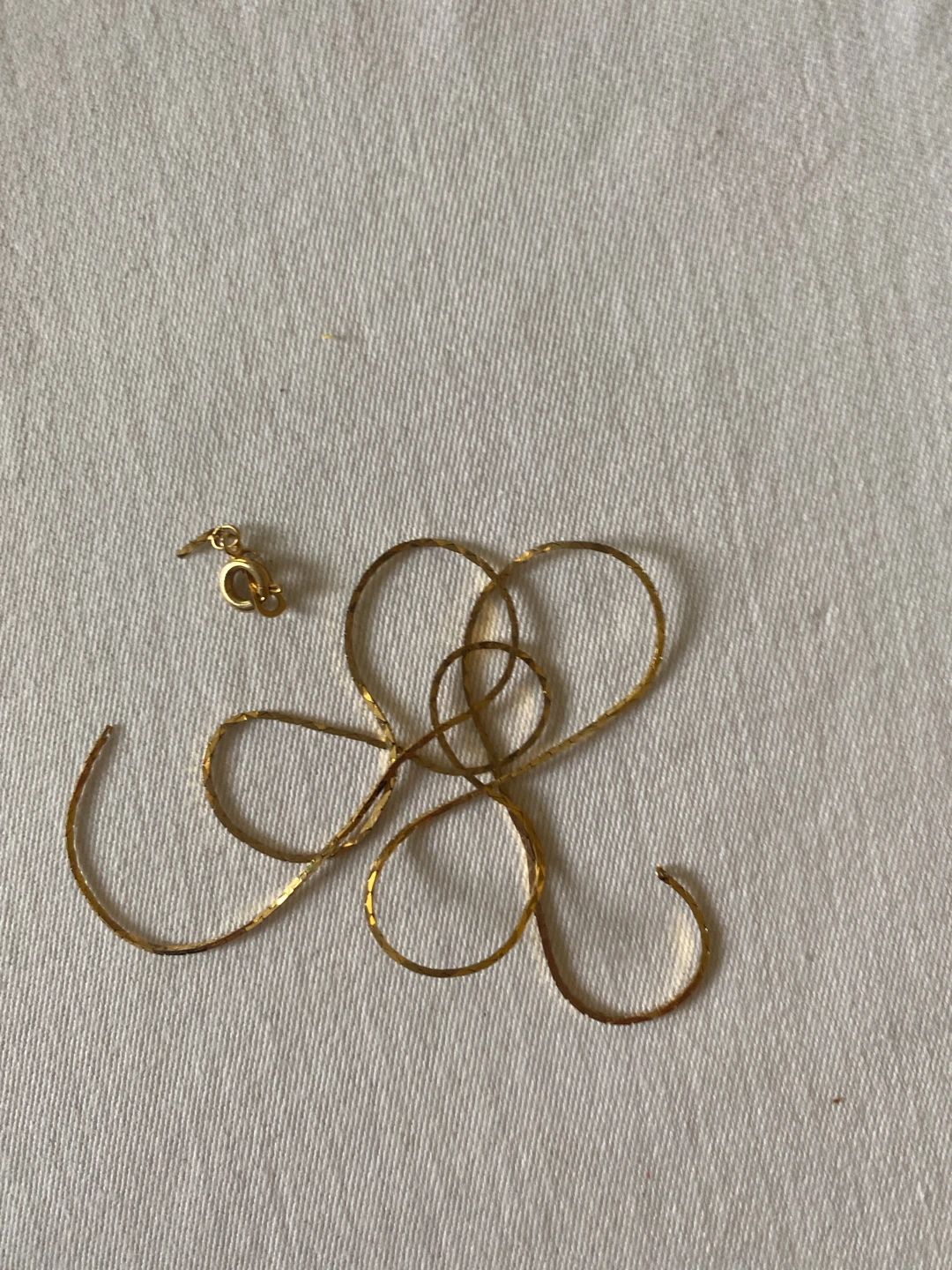 Gold-tone flat chain with spring ring clasp, likely from a necklace or bracelet